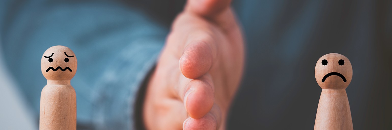 Houten poppetjes met bezorgde gezichtsuitdrukkingen gescheiden door een hand, symboliserend de verdeling van vermogen bij een echtscheiding of het vernietigen van een scheidingsconvenant.